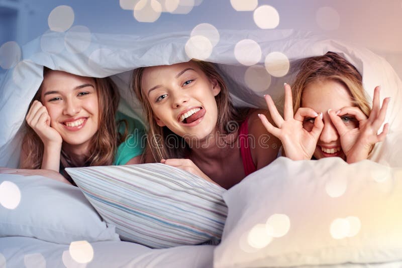 Szczęśliwe młode kobiety w łóżko piżamy przyjęciu w domu