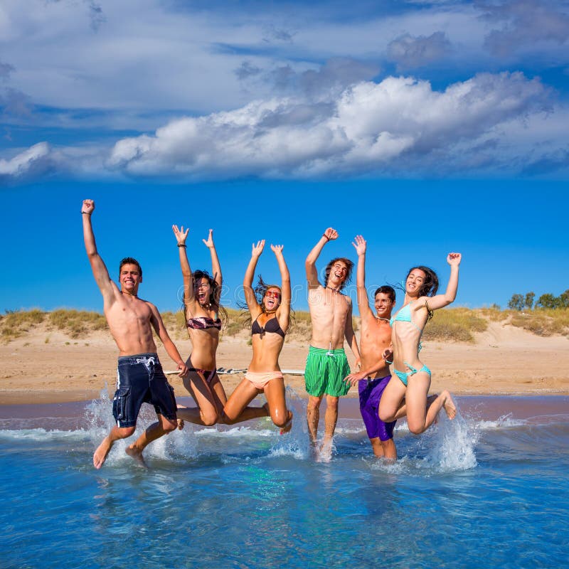 Happy excited teen boys and girls group jumping at the beach splashing water. Happy excited teen boys and girls group jumping at the beach splashing water