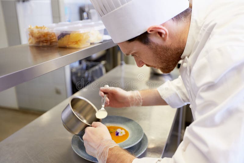 Szczęśliwego męskiego szefa kuchni kulinarny jedzenie przy restauracyjną kuchnią fotografia stock Szczęśliwego męskiego szefa kuchni kulinarny jedzenie przy restauracyjną kuchnią fotografia stock