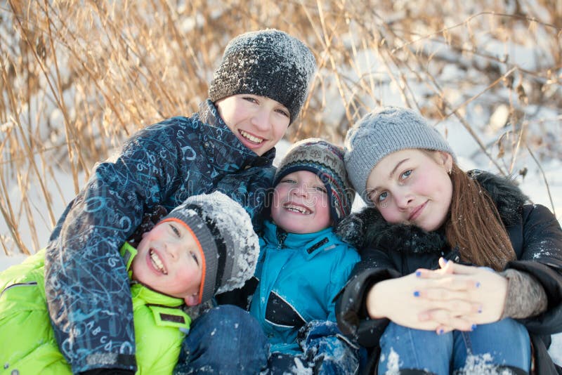 Szczęśliwi dzieci śmia się w winterwear podczas gdy bawić się w snowdrift zdjęcie royalty free Szczęśliwi dzieci śmia się w winterwear podczas gdy bawić się w snowdrift zdjęcie royalty free