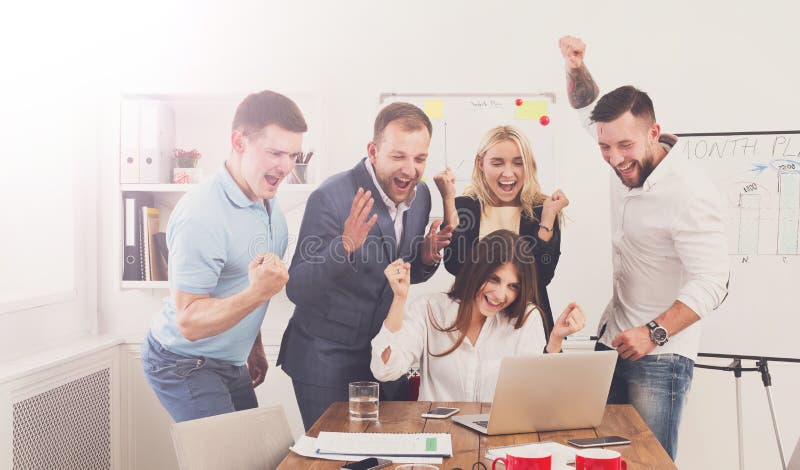 Happy business people celebrate success looking at laptop screen in the office. Successful corporate team of partners and coworkers, winners excited of victory. Happy business people celebrate success looking at laptop screen in the office. Successful corporate team of partners and coworkers, winners excited of victory