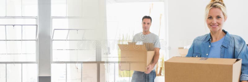 Szczęśliwi pary chodzenia pudełka w ich nowym domu zdjęcie stock Szczęśliwi pary chodzenia pudełka w ich nowym domu zdjęcie stock