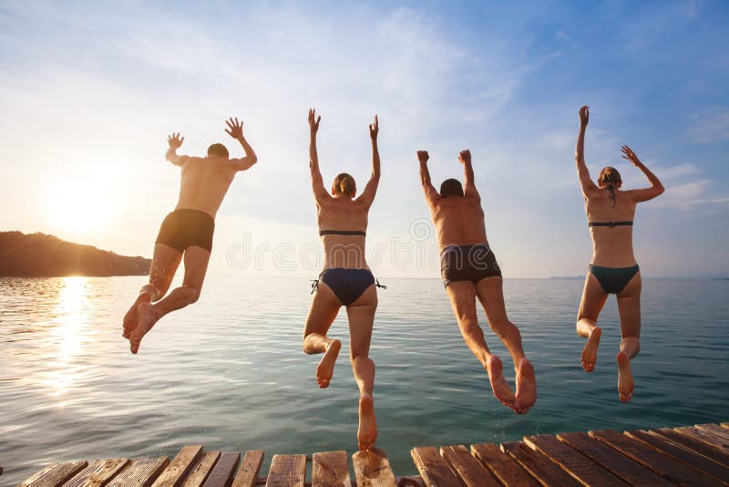 Szczęśliwi plażowi wakacje, grupa przyjaciele skacze woda