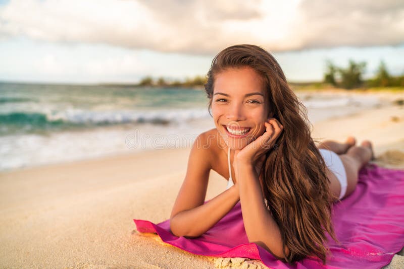 Szczęśliwy Azjatycki bikini wwoman model relaksuje na wakacje lying on the beach na plażowym ręczniku, Hawaje