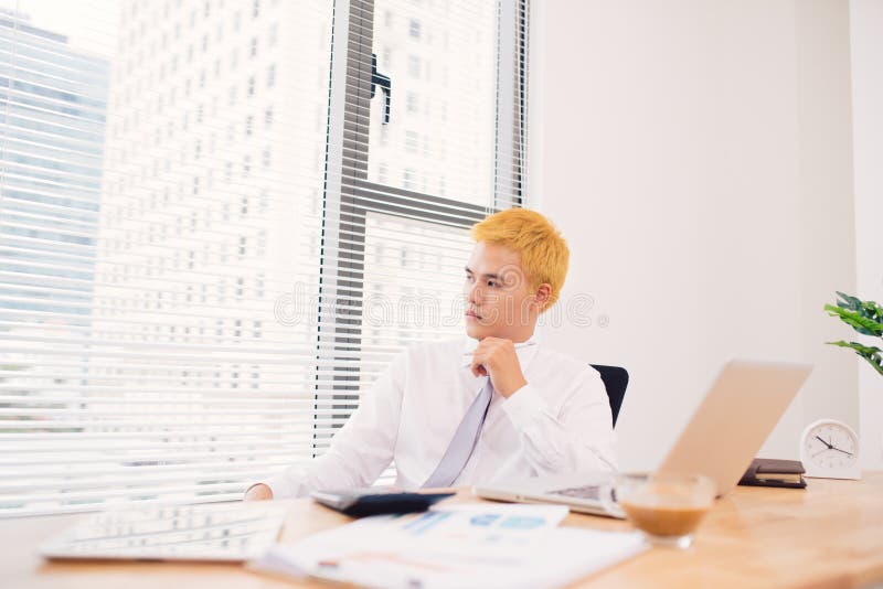 Szczęśliwy biznesmen pracuje przy jego biurem z laptopem Młody smili zdjęcia stock Szczęśliwy biznesmen pracuje przy jego biurem z laptopem Młody smili zdjęcia stock
