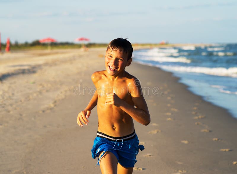 Szczęśliwy chłopiec bieg na dennej plaży przy latem obraz stock Szczęśliwy chłopiec bieg na dennej plaży przy latem obraz stock