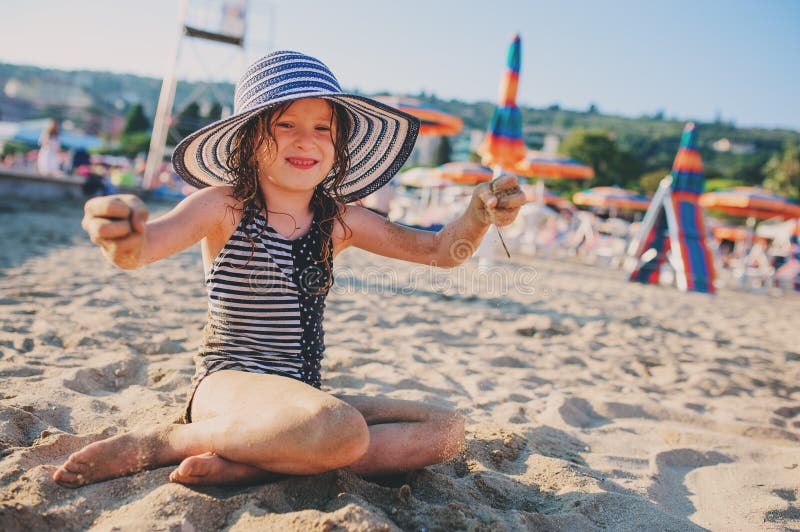 Szczęśliwy dziecko relaksuje na lato plaży i bawić się z piaskiem w swimsuit Grże pogodowego, wygodnego nastrój, zdjęcia royalty free Szczęśliwy dziecko relaksuje na lato plaży i bawić się z piaskiem w swimsuit Grże pogodowego, wygodnego nastrój, zdjęcia royalty free