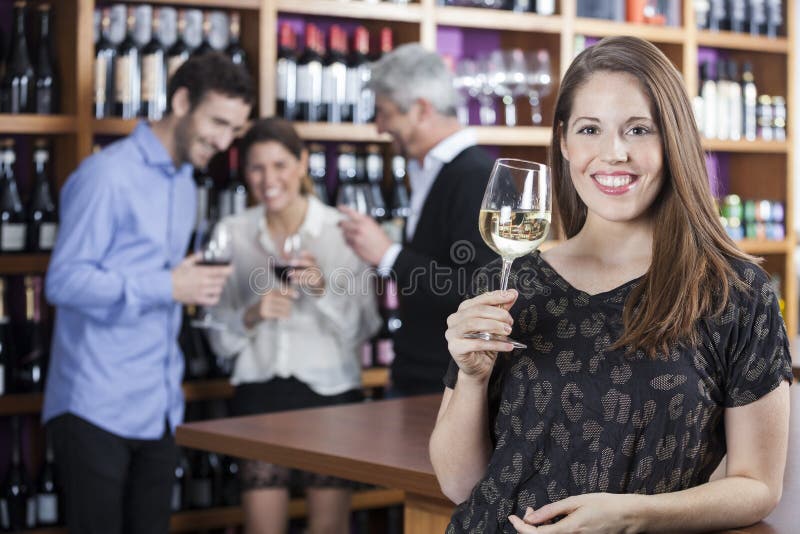 Szczęśliwy kobiety mienia Wineglass Z przyjaciółmi W tle zdjęcie royalty free Szczęśliwy kobiety mienia Wineglass Z przyjaciółmi W tle zdjęcie royalty free
