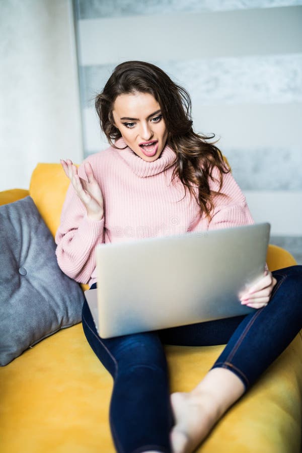 Szczęśliwy kobiety obsiadanie na leżance używać jej laptop w żywym pokoju w domu obrazy royalty free Szczęśliwy kobiety obsiadanie na leżance używać jej laptop w żywym pokoju w domu obrazy royalty free