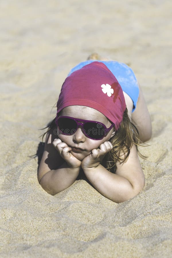Szczęśliwy małej dziewczynki lying on the beach na piasku na plaży obraz stock Szczęśliwy małej dziewczynki lying on the beach na piasku na plaży obraz stock