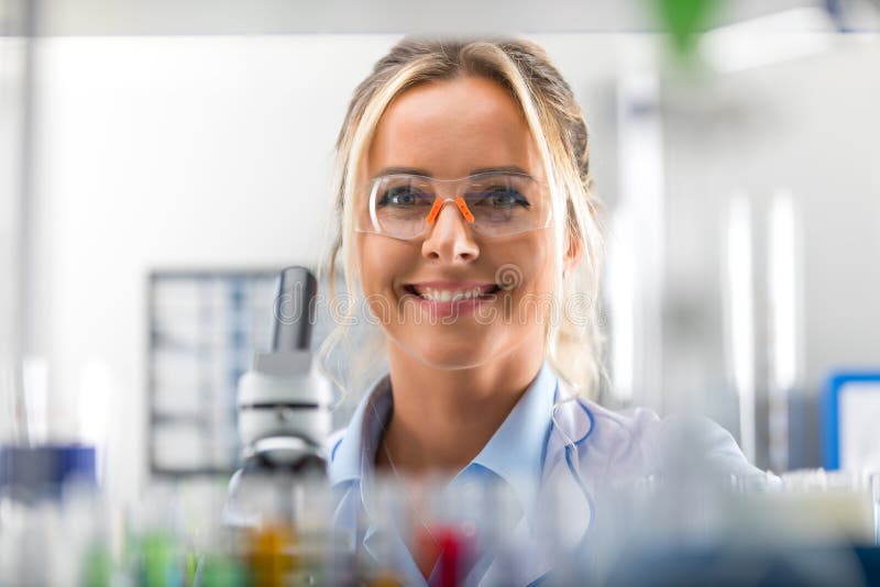 Szczęśliwy młody atrakcyjny uśmiechnięty kobieta naukowiec w laboratorium obraz stock
