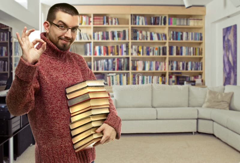 Szczęśliwy młody człowiek w szkłach z książkami przy biblioteką obrazy stock Szczęśliwy młody człowiek w szkłach z książkami przy biblioteką obrazy stock