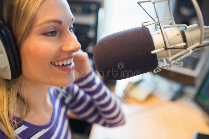 Szczęśliwy młody żeński radiowy gospodarza transmitowanie w studiu