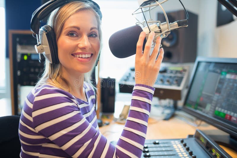 Szczęśliwy młody żeński radiowy gospodarza transmitowanie w studiu