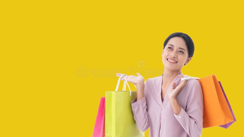 Szczęśliwy piękny Azjatycki kobieta uśmiech dwa wręcza mienie torby na zakupy zdjęcie stock Szczęśliwy piękny Azjatycki kobieta uśmiech dwa wręcza mienie torby na zakupy zdjęcie stock