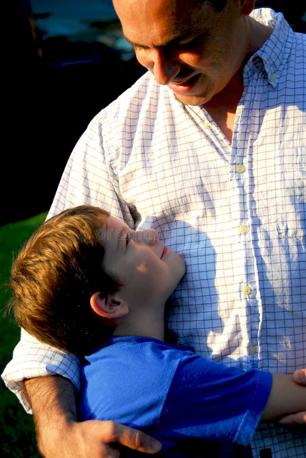 Son and father looking at each other and smiling. Son and father looking at each other and smiling