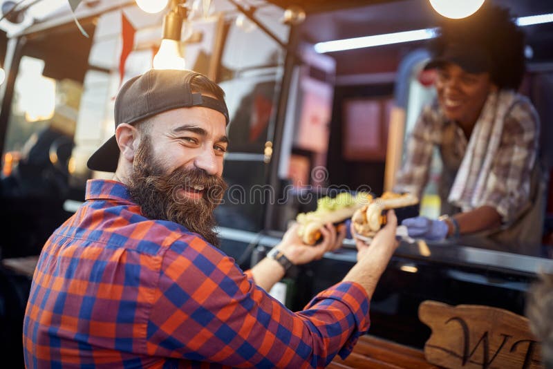 Szczęśliwy, usatysfakcjonowany kaukaski mężczyzna biorący kanapki od uprzejmego pracownika w fast food, patrząc na kamerę obrazy royalty free
