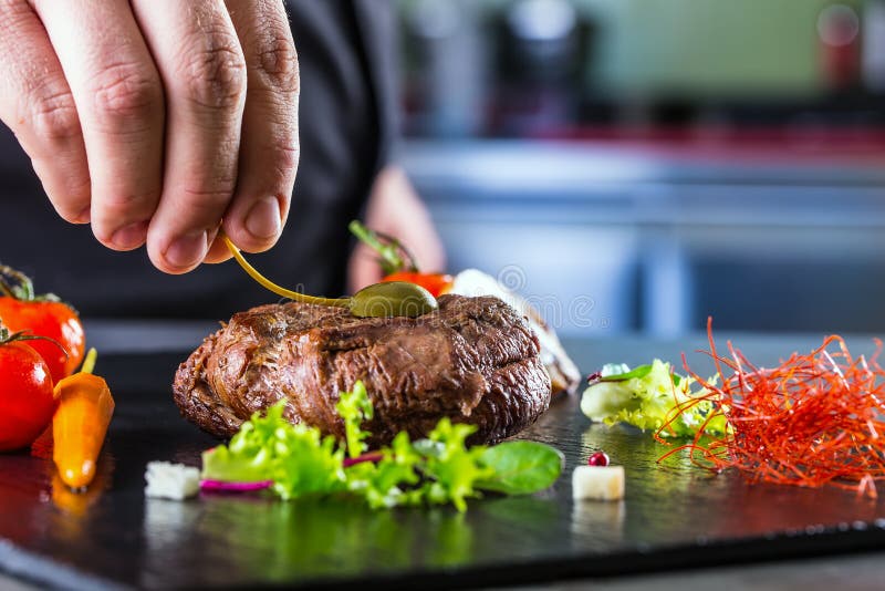 Szef kuchni w hotelowym lub restauracyjnym kuchennym kucharstwie ręka, tylko Przygotowany wołowina stek z jarzynową dekoracją