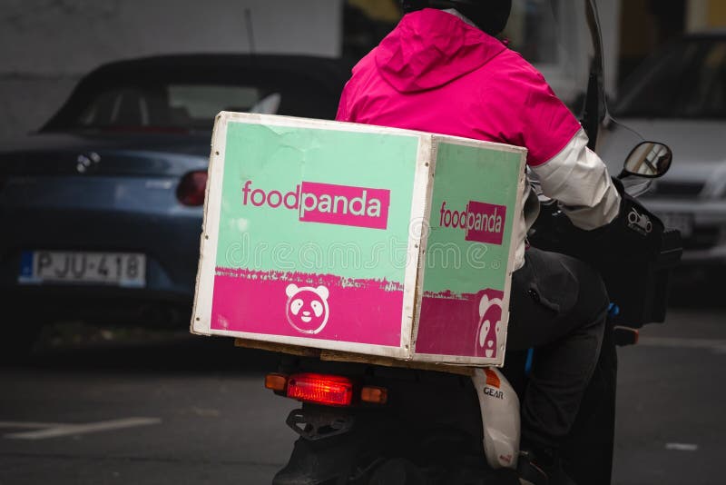 Picture of a food delivery guy from Foodpanda in the streets of Szeged, Hungary. Foodpanda is an online food and grocery delivery platform owned by Berlin-based Delivery Hero. Foodpanda operates as the lead brand for Delivery Hero in Asia, with its headquarters in Singapore. Picture of a food delivery guy from Foodpanda in the streets of Szeged, Hungary. Foodpanda is an online food and grocery delivery platform owned by Berlin-based Delivery Hero. Foodpanda operates as the lead brand for Delivery Hero in Asia, with its headquarters in Singapore