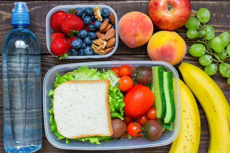 School lunch boxes with sandwich, fresh fruits and vegetables, berries and nuts and bottle of water. Top view. School lunch boxes with sandwich, fresh fruits and vegetables, berries and nuts and bottle of water. Top view