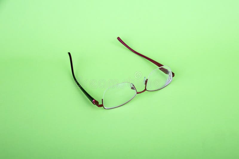 Glasses of a woman on a green background. Red frame glasses on green background. Myopia and hyperopia. Red rim glasses.