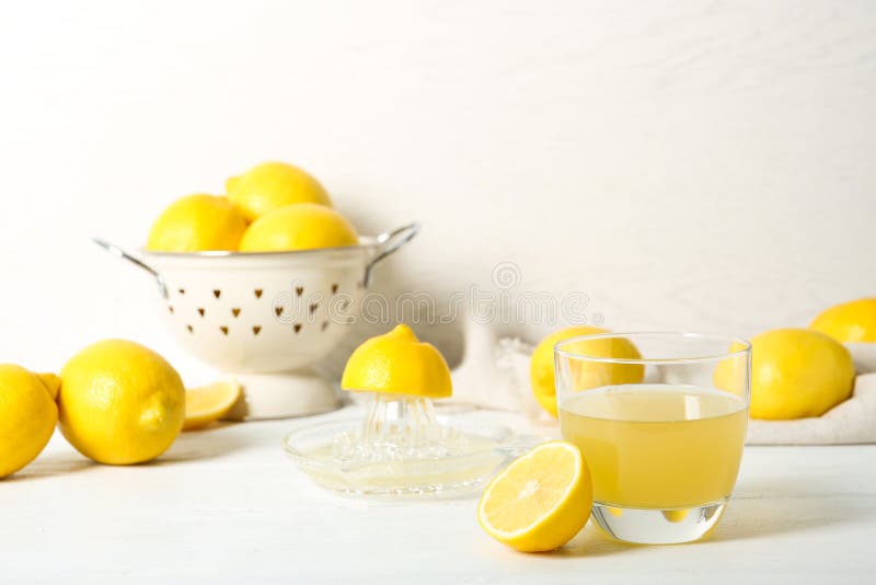 Glass of lemon juice and fresh fruit on light table. Glass of lemon juice and fresh fruit on light table