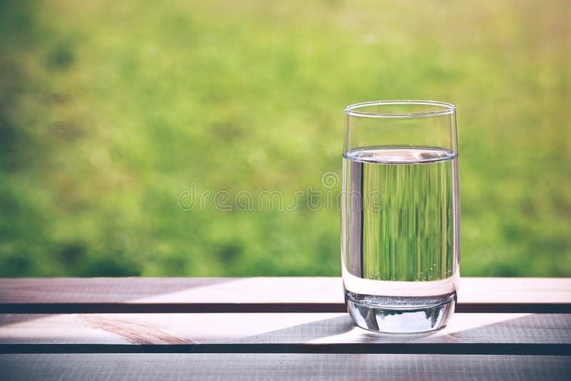 Szkło czysta woda na zielonym naturalnym tle obrazy stock Szkło czysta woda na zielonym naturalnym tle obrazy stock
