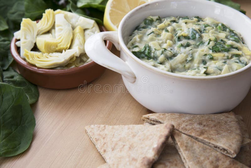 Bowl of vegan spinach artichoke dip with pita and ingredients. Bowl of vegan spinach artichoke dip with pita and ingredients