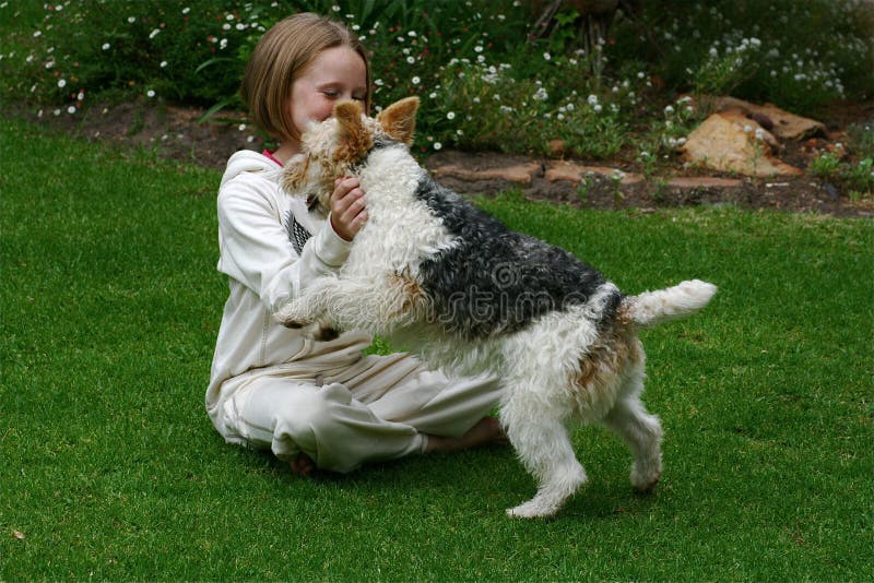 A white caucasian girl child with her playful puppy pet in the garden. A white caucasian girl child with her playful puppy pet in the garden