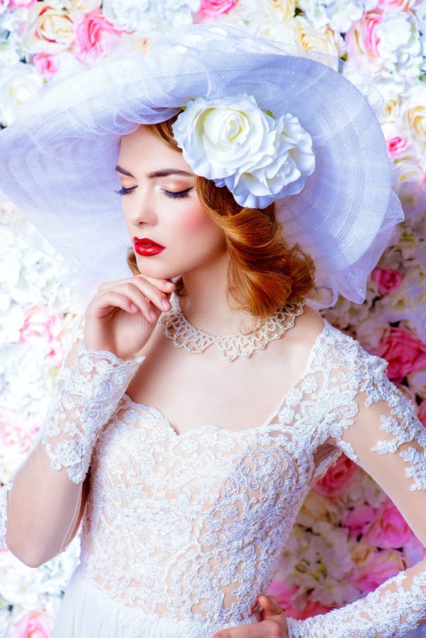 Portrait of a beautiful bride woman in elegant lace dress and broad-brimmed hat posing over floral background. Wedding. Beauty, fashion concept. Portrait of a beautiful bride woman in elegant lace dress and broad-brimmed hat posing over floral background. Wedding. Beauty, fashion concept.