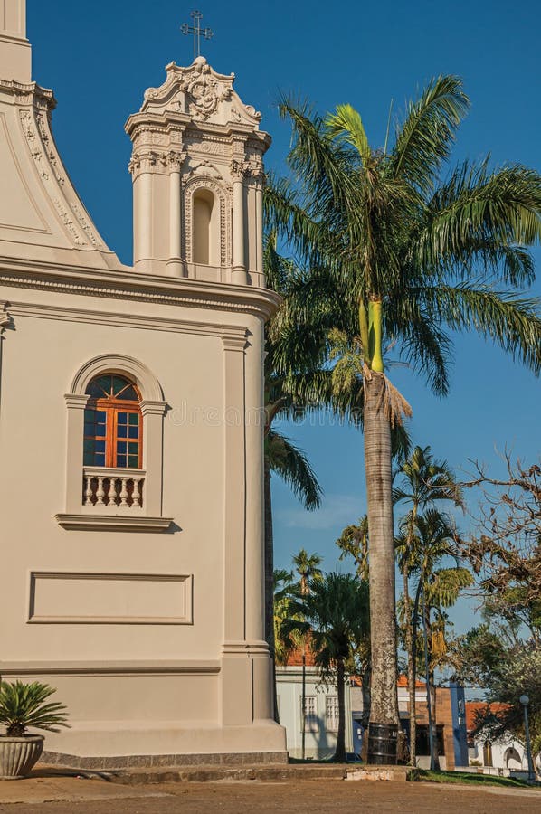 Detail of church corner and palm tree in front of a cobblestone square at SÃ£o Manuel.