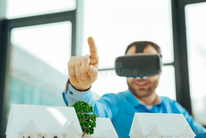 Säker specialist som pekar upp hans finger och bär virtuell verklighetexponeringsglas royaltyfria foton