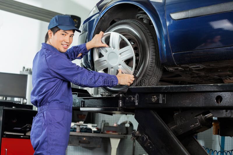 Säkert gummihjul för mekanikerFixing Hubcap To bil fotografering för bildbyråer Säkert gummihjul för mekanikerFixing Hubcap To bil fotografering för bildbyråer