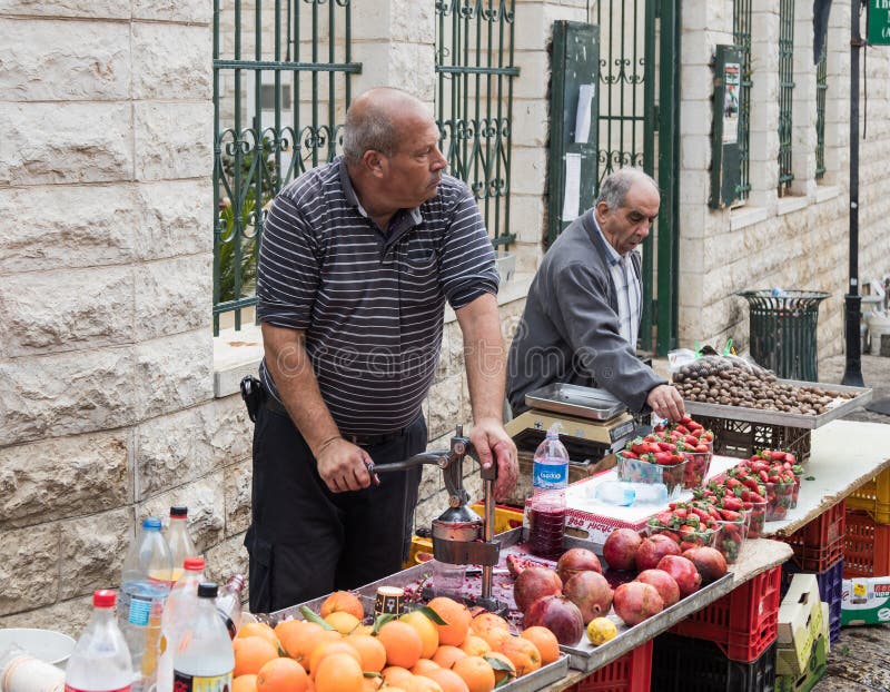 Säljaren gör nytt sammanpressad granatäpplefruktsaft i den östliga basaren i den gamla staden av Nazareth i Israel royaltyfria bilder Säljaren gör nytt sammanpressad granatäpplefruktsaft i den östliga basaren i den gamla staden av Nazareth i Israel royaltyfria bilder