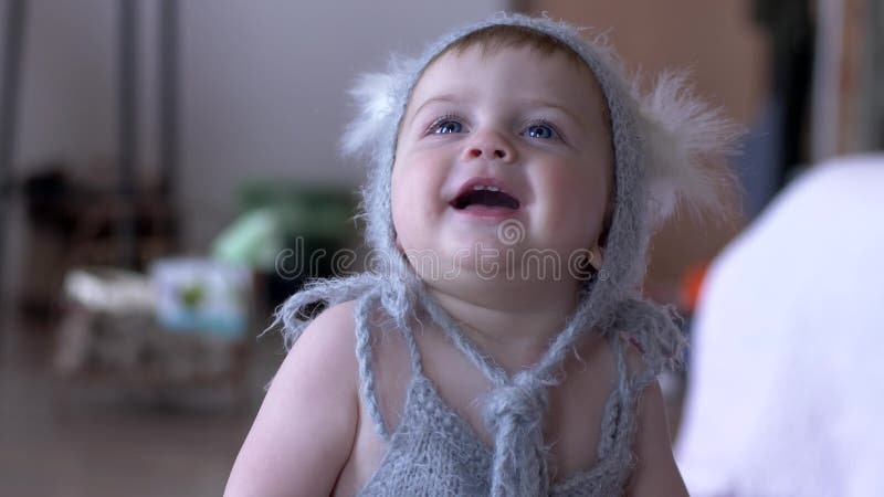 Säuglingsspaß, nettes Kleinkind im Abendkleid lachend auf unfocused Hintergrund