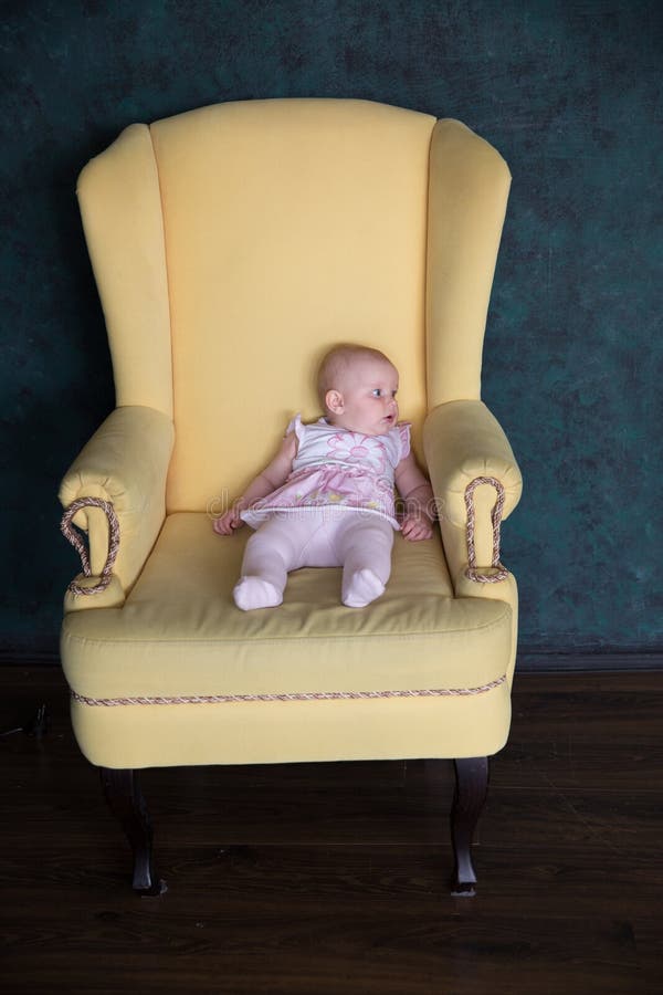 Séance de bébé sur le grand fauteuil dans le studio photo stock Séance de bébé sur le grand fauteuil dans le studio photo stock