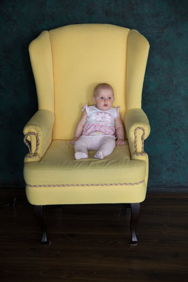 Séance de bébé sur le grand fauteuil dans le studio photo stock Séance de bébé sur le grand fauteuil dans le studio photo stock