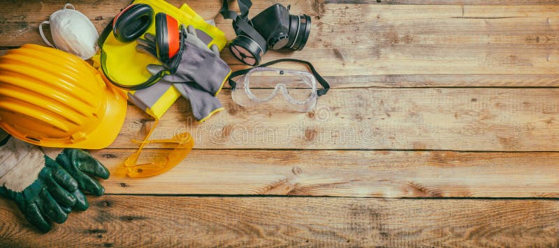 Construction safety. Protective hard hat, headphones, gloves and glasses on wooden background, banner, copy space, top view. Construction safety. Protective hard hat, headphones, gloves and glasses on wooden background, banner, copy space, top view