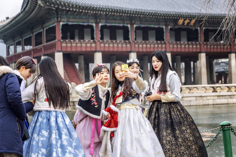 Séoul, Corée du Sud, 12/30/2017 : Les filles coréennes dans les hanboks prennent un selfie en parc d'hiver Plan rapproch? images stock Séoul, Corée du Sud, 12/30/2017 : Les filles coréennes dans les hanboks prennent un selfie en parc d'hiver Plan rapproch? images stock