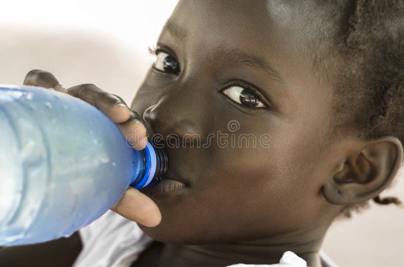 Símbolo da pobreza: Menina preta africana que bebe a água fresca coberta de urzes