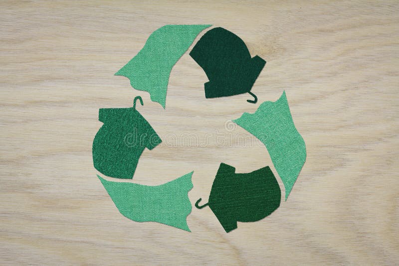 Símbolo de la ropa de reciclaje señalización de la reutilización textil en un fondo de madera concepto de moda sostenible