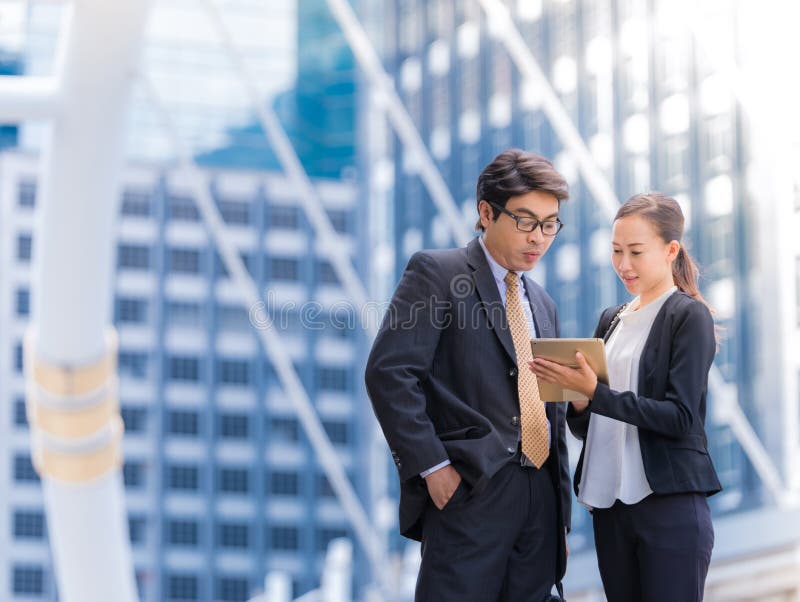 Sócios comerciais de ajuda de Confident do chefe do secretário que consultam no fundo da cidade imagens de stock Sócios comerciais de ajuda de Confident do chefe do secretário que consultam no fundo da cidade imagens de stock
