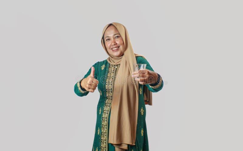 Sömmande kvinnor i traditionell grön klänning som ger tummen upp medan man håller ett glas arkivbild