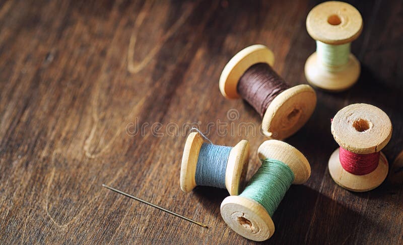 Sewing thread on a wooden background. Set of threads on bobbins retro style. Vintage accessories for sewing on the tabler. Sewing thread on a wooden background. Set of threads on bobbins retro style. Vintage accessories for sewing on the tabler
