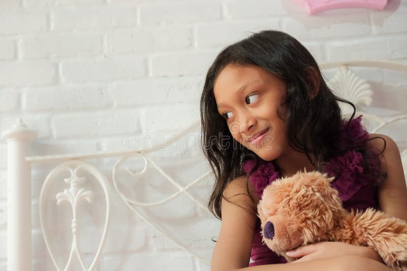 Söt asiatisk liten flicka på sängen Känn sig glad för att hon är Teddy Bear royaltyfri foto