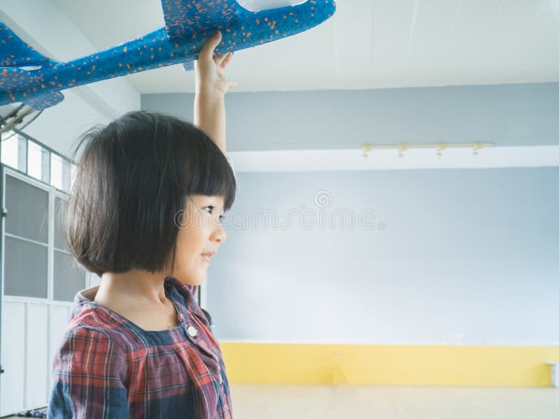Söt asiatisk liten flicka som spelar flygplansleksak inomhus i hemmet royaltyfri fotografi