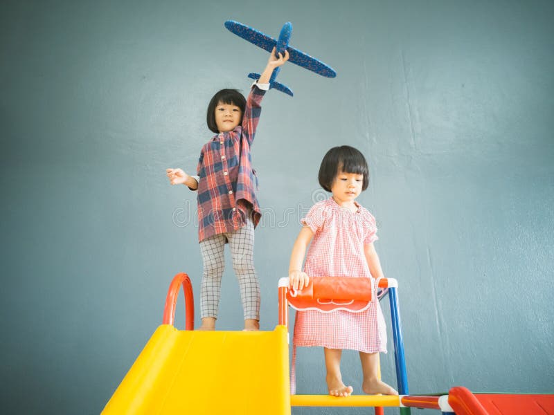 Söt asiatisk liten flicka som spelar flygplansleksak inomhus i hemmet fotografering för bildbyråer