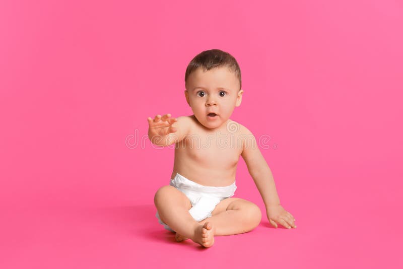 Söt barn i torr, mjuk diaper sittande på rosa bakgrund. Söt barn i torr, mjuk blöjor sittande