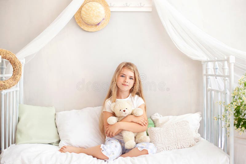 Söt, blonde liten flicka kraggar teddy björn copyspace. barnomsorg. Barnteddybjörn tittar på kameran och ler medan du sitter royaltyfri fotografi
