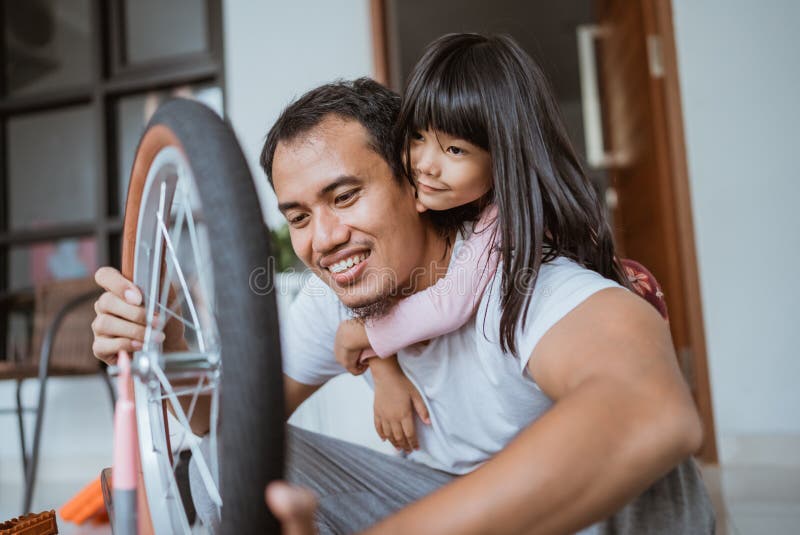 Söt dotter kramar sin far medan hon installerar ett hjul arkivbilder